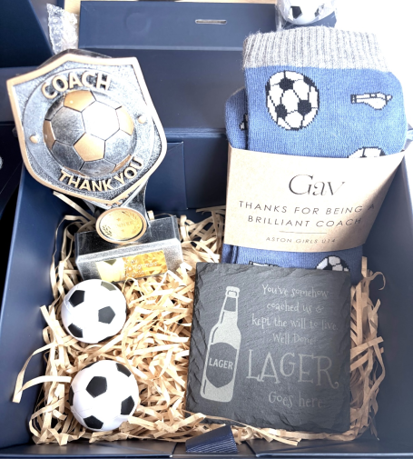 Football Coach gift boxes made to order with personalised items. A gift box containing football-themed items, including socks, a medal, and small balls.