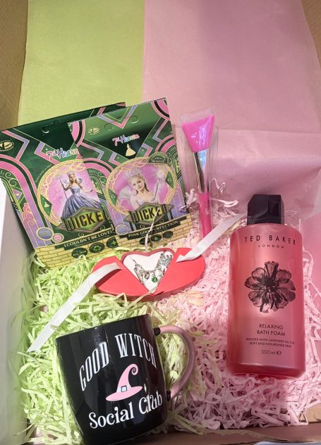Wicked themed gift box for a big Wicked fan - the box included a witch themed charm bracelet and pamper items plus a "Good Witch" coaster. Gift box containing a mug, shower gel, lip gloss, and snacks on pink and green packing.
