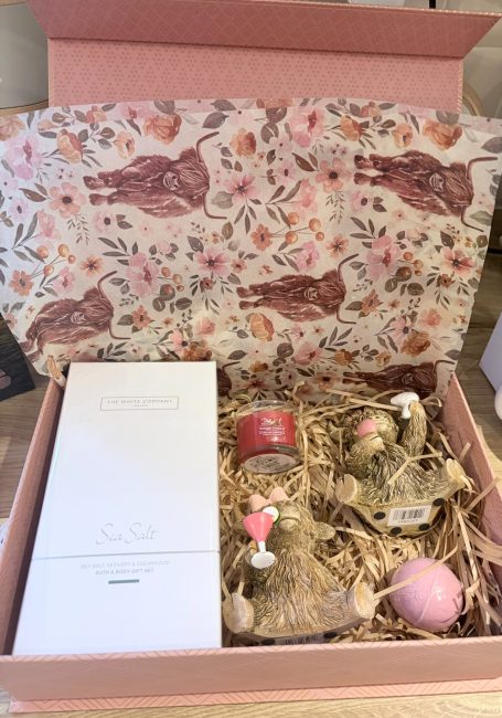 A get well soon gift box from my customer in Australia to her Sister in Leeds - the spec was she loves highland cows and home scents. Gift box featuring decorative items, including two small glass jars and a pink ornament.